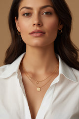 Brunette woman wearing CharmFlip gold layered necklaces over a white shirt