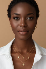Woman wearing CharmFlip gold layered necklaces with charm pendants over a white shirt