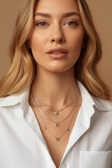 Blonde woman wearing CharmFlip silver layered necklaces with charm pendants over a white shirt