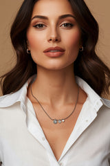 Brunette woman wearing CharmFlip silver charm necklace over a white shirt